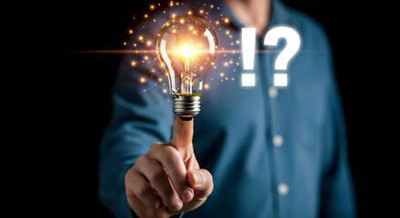 A finger points to a glowing incandescent light bulb symbolizing a brilliant idea or innovation with a question mark and exclamation point suggesting discovery and realization