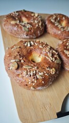 Freshly baked seed-topped bagels sit on a wooden board. This image conveys the concept of homemade baking and wholesome artisan bread