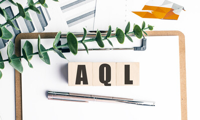 AQL Acceptable Quality Limit acronym on wooden blocks with clipboard, charts, pen, and plant on white office desk