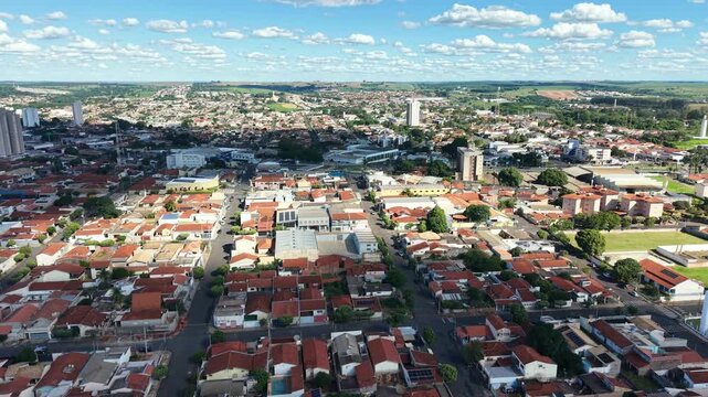 Aerial view shows a cityscape with buildings, houses, and green landscape