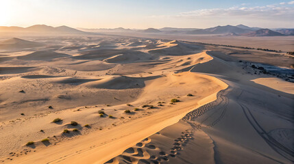 Golden hour light over vast desert sand dunes and mountains