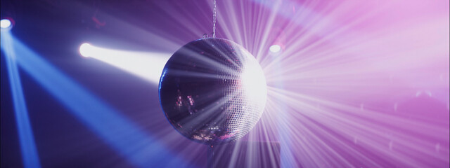 Disco ball reflects colorful lights during night party in a vibrant club atmosphere
