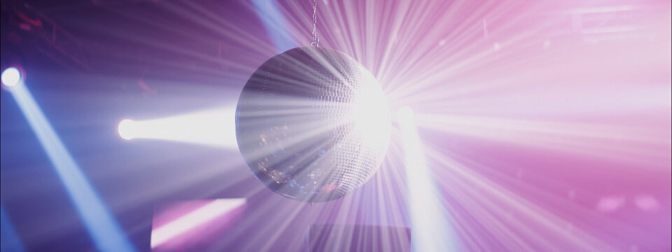 Disco ball reflecting colorful lights at a lively dance party in a club at night - Powered by Adobe