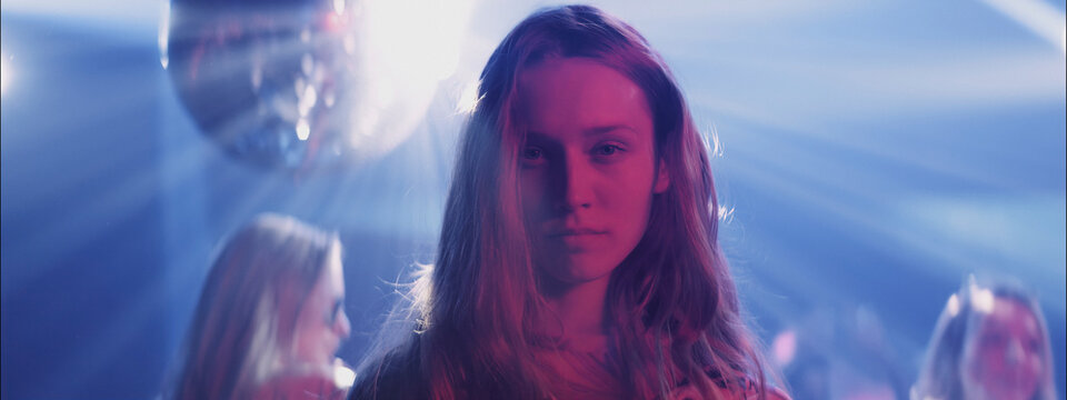 Dancer in a vibrant nightclub with colorful lights and a disco ball during a lively evening event
