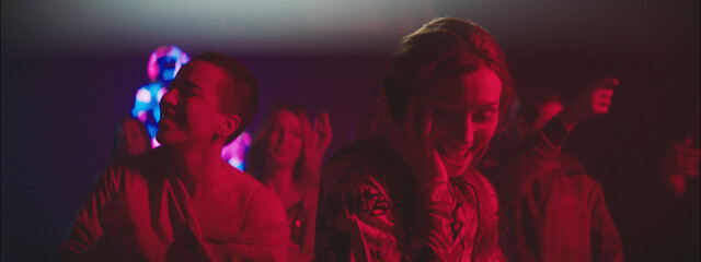 People dancing joyfully at a colorful party in a dimly lit venue during the late evening hours