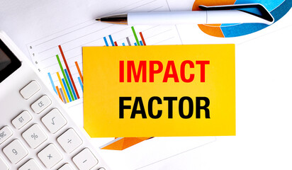  Impact factor phrase on yellow card with calculator, charts and pen on white office desk