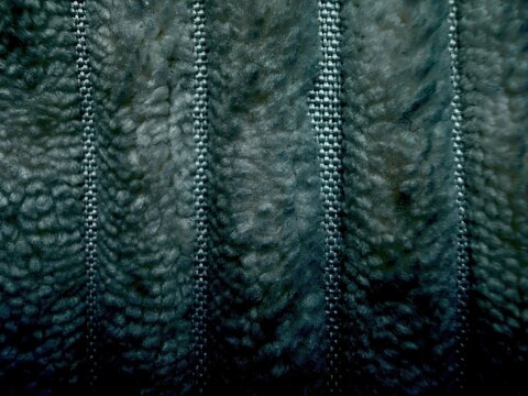 close-up of parallel silver zipper teeth on dark blue fuzzy fabric texture background
