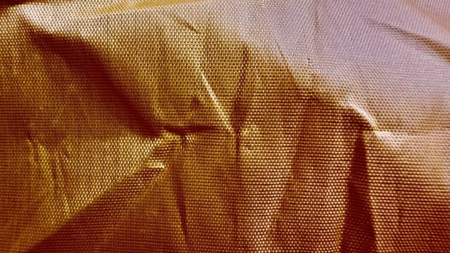 close-up of crumpled golden bubble wrap texture with wrinkled folds and shiny dotted pattern
