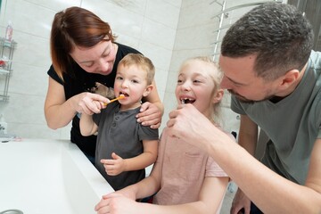 Parents helping to kids brush their teeth. Happy family