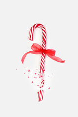 A red and white candy cane tied with a bright red ribbon is shown partially broken, with fragments scattered around. This captures the spirit of holiday celebrations and treats.