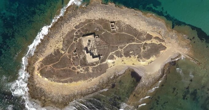 Aerial perpendicular view of Isola delle Correnti, located near Portopalo in the province of Syracuse, Sicily, Italy. It is a small, rocky, uninhabited island in the crystalline Mediterranean Sea.