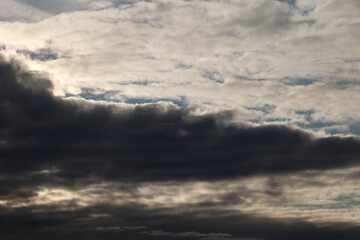 Heavy Grey Clouds Covering The Sky With A Glimpse Of Sunlight breaking Through. Atmospheric Weather Texture.