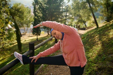 Active Woman Stretching Outdoors in Hijab During Morning Exercise in Park