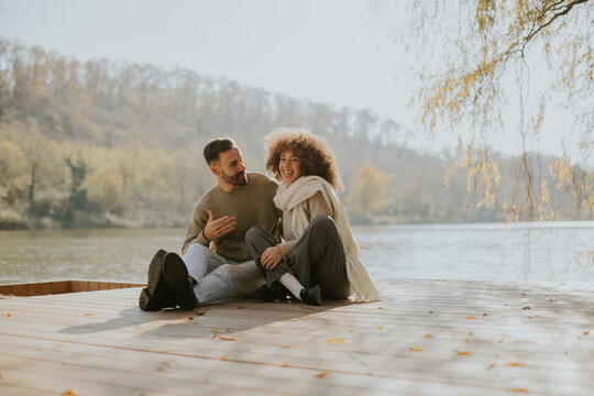 Couple enjoying a peaceful moment by the serene lakeside during autumn afternoon