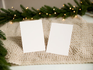Cozy Winter Card Duo Mockup on Knitted Blanket with Evergreen Branches and Soft Holiday Lights