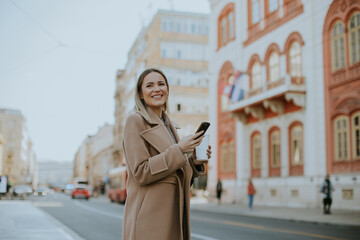 Woman with smartphone enjoys the city streets in daytime