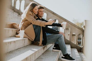 Couple enjoying a sunny day on steps while sharing a moment with their phones