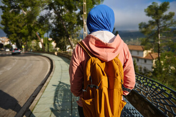 Fototapeta premium Muslim Woman With Hijab Standing On City Bridge With Backpack In Europe