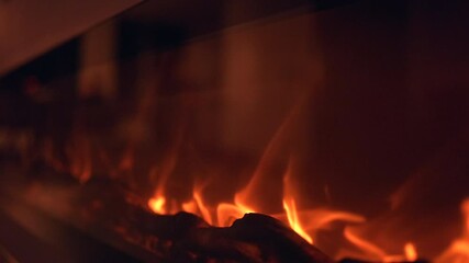Close up view of warm orange fireplace flames flickering over dark logs creating a cozy glowing background for winter relaxation holidays and home comfort. - Powered by Adobe