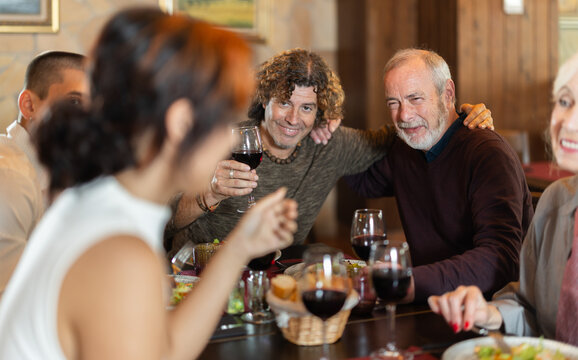 Multi-generation family discussing daily life while having fresh food and wine in restaurant