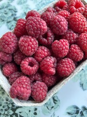 Fresh Ripe Red Raspberries in a Cardboard Container. Ripe red raspberries filling a small, eco-friendly paper or cardboard container.
