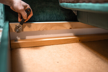 Man disassembling sofa furniture mechanism at home using furniture wrench. DIY Assembling Furniture concept.