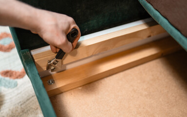 Man disassembling sofa furniture mechanism at home using furniture wrench. DIY Assembling Furniture concept.