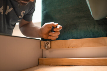 Man disassembling sofa furniture mechanism at home using furniture wrench. DIY Assembling Furniture concept.