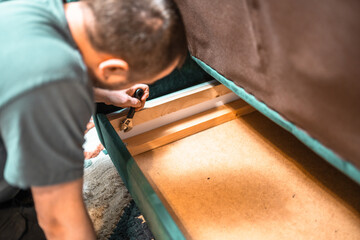 Man disassembling sofa furniture mechanism at home using furniture wrench. DIY Assembling Furniture concept.