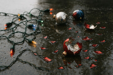 Broken Christmas toys and a wet garland on the wet asphalt.