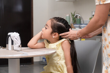 Mother styling daughter's long hair at home