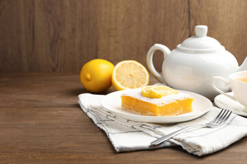 Tasty lemon bar with powdered sugar served on wooden table. Space for text
