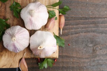 Fresh garlic and parsley on wooden table, flat lay. Space for text