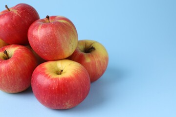Ripe red apples on light blue background, closeup. Space for text