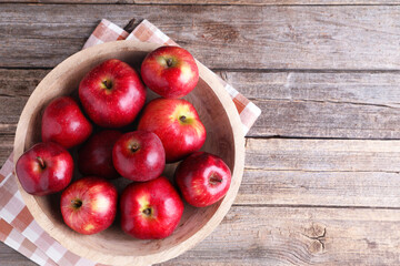 Ripe red apples in bowl on wooden table, top view. Space for text