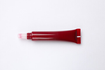 Beautiful dark red lip gloss on white background, top view