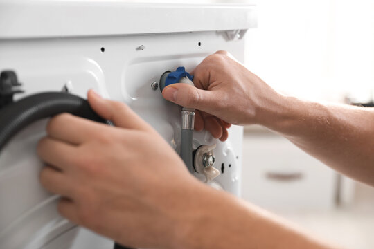Repairman fixing broken washing machine at home, closeup