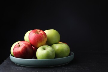 Fresh red and green apples on dark textured table against black background, closeup. Space for text