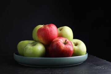Fresh red and green apples on dark textured table against black background, closeup
