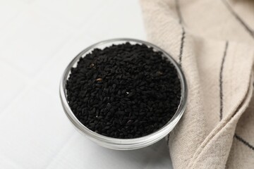 Aromatic black caraway in glass bowl on white table, closeup