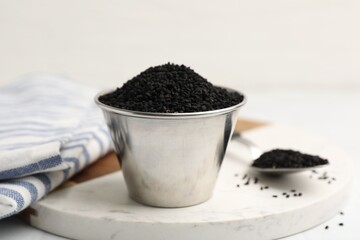 Aromatic black caraway in bowl and spoon on white table, closeup