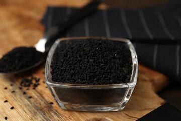 Aromatic black caraway in glass bowl and spoon on table, closeup