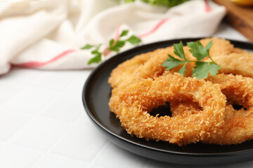 Deep fried squid rings with parsley on white tiled table, closeup. Space for text