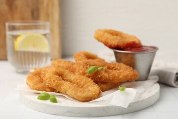 Deep fried squid rings with basil and ketchup on white tiled table, closeup
