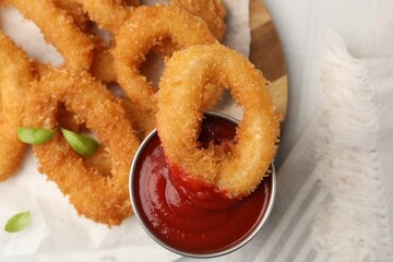 Deep fried squid rings with basil and ketchup on table, closeup