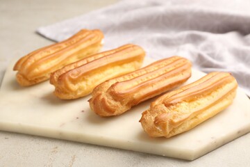 Fresh tasty eclairs on light table, closeup