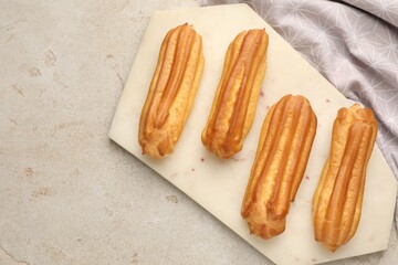 Fresh tasty eclairs on light table, top view. Space for text