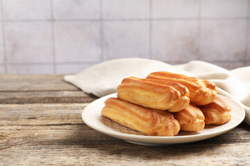Fresh tasty eclairs on wooden table, closeup. Space for text