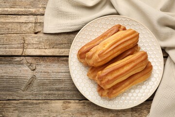Fresh tasty eclairs on wooden table, top view. Space for text