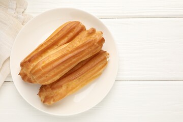 Tasty eclairs on white wooden table, top view. Space for text